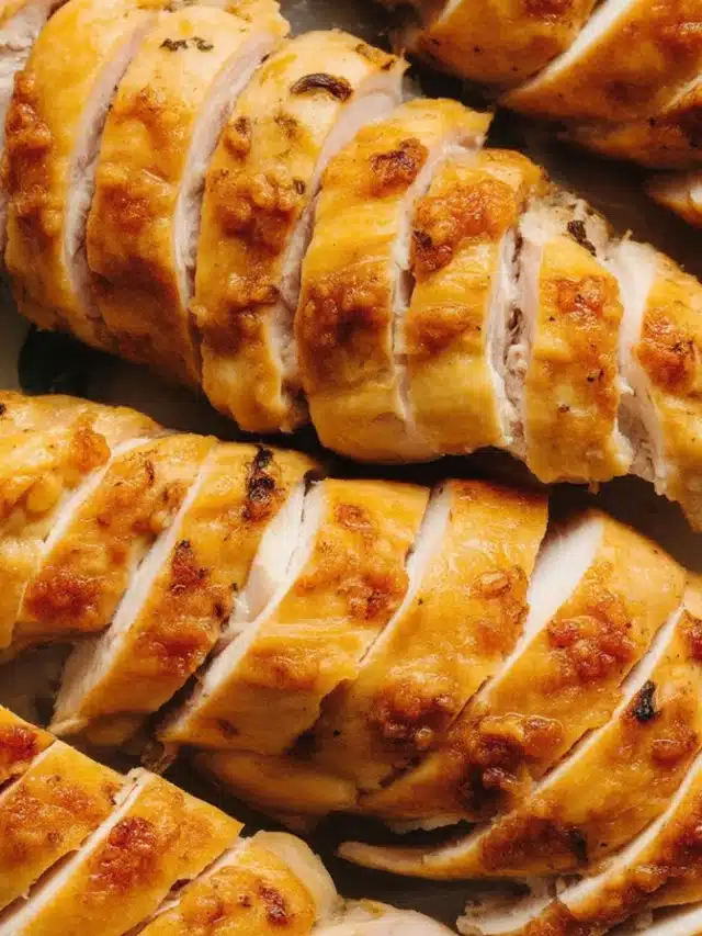 Juicy slow-cooked chicken breast in a crock pot topped with herbs and spices.