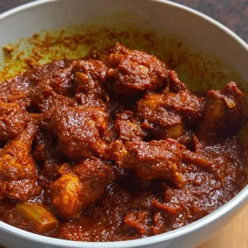 Delicious Chicken Ghee Roast served on a plate garnished with herbs.