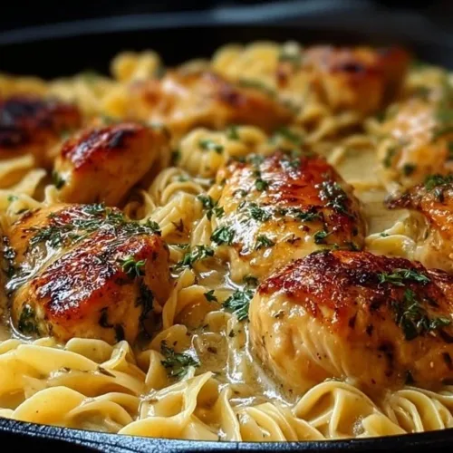 Juicy one-pan chicken served with creamy buttered noodles on a plate.
