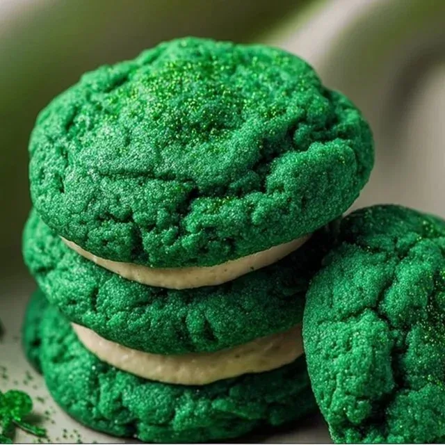 Plate of freshly baked green velvet cookies topped with cream cheese frosting