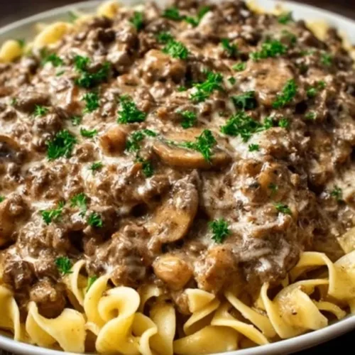 Creamy ground beef stroganoff served with noodles and garnished with parsley