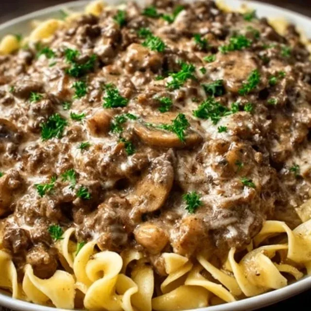 Creamy ground beef stroganoff served with noodles and garnished with parsley