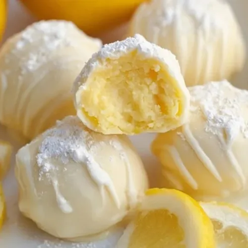 Delicious homemade lemon truffles on a white plate, garnished with lemon zest.