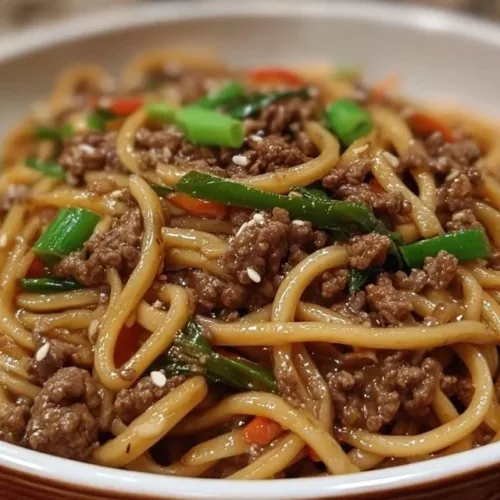 A delicious plate of Mongolian Ground Beef Noodles garnished with green onions.
