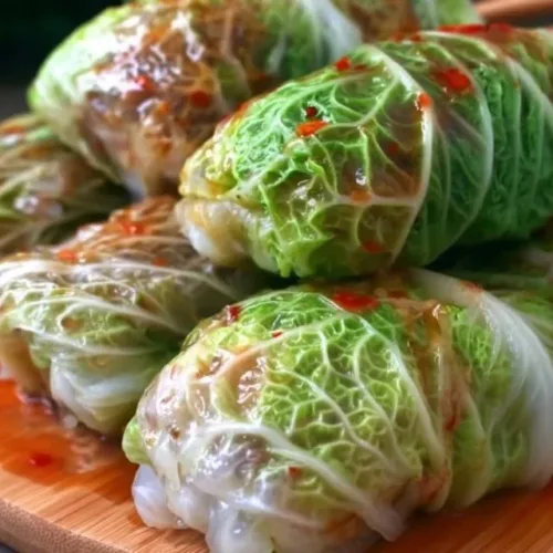 Napa cabbage rolls filled with savory ingredients on a rustic plate.