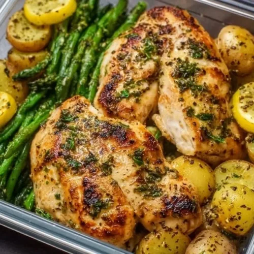 Lemon garlic chicken meal prep with fresh herbs and vegetables