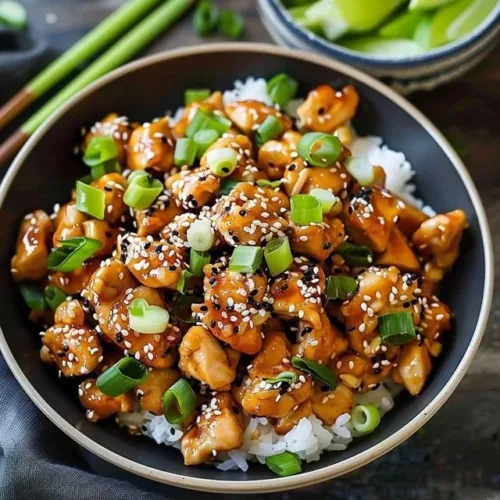 Plate of sesame ground chicken garnished with sesame seeds and green onions