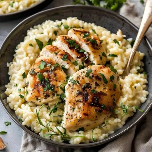 Creamy garlic herb chicken risotto served in a white bowl with fresh herbs