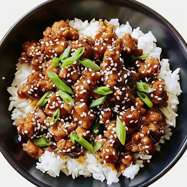 A delicious plate of sesame ground chicken garnished with sesame seeds and green onions.