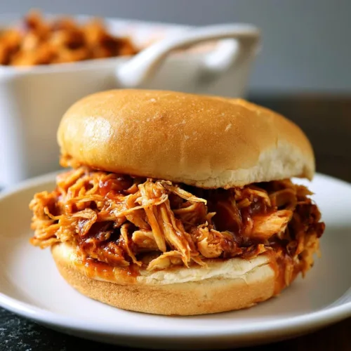 Delicious crockpot BBQ chicken served on a plate with garnish.